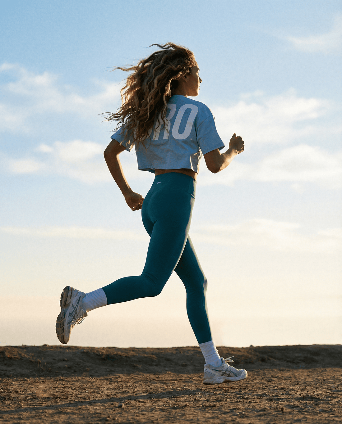 Femme qui court au lever du soleil en crop top et legging de sport BRO Apparel